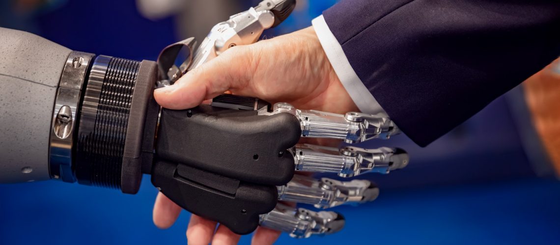 Hand of a businessman shaking hands with a Android robot.